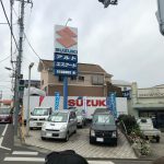 Picture of car dealer lot shows it is very small with a giant sign.