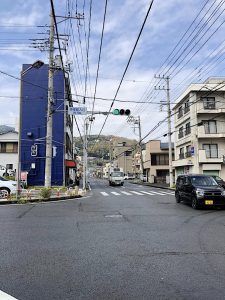 Street intersection with blue building on the left and the hill raising in the background.